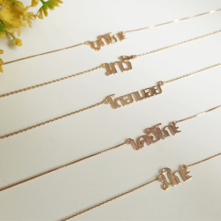 Thai name necklaces in gold, laid out together